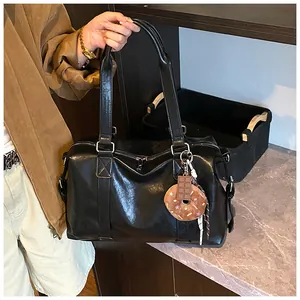 Close-up of black PU leather travel bag with zipper and cute donut charms