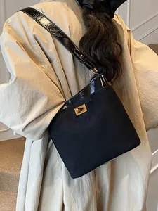 Zwarte bucket bag in matte uitvoering met laklederen bies gedragen door een vrouwelijk model