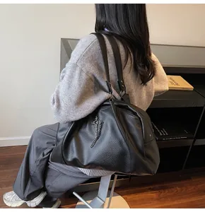 Rear view of a model sitting with a black pebble leather tote bag and cross pendants