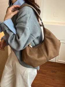 Bruine faux suède hobo tas met houten kralen hanger, getoond door model in een zachte studio