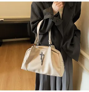 Detail of beige litchi grain leather tote with metal cross and chain decoration