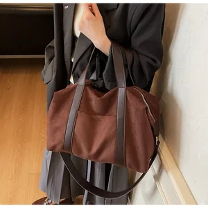Detail of dark brown suede tote bag featuring a front pocket and versatile shoulder strap