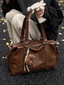 Large dark brown faux leather travel tote bag with donut pendant in autumn outdoor setting