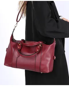 Side view of dark burgundy pebble leather tote bag featuring gold hardware and strap detail