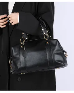 Detailed view of black lychee leather tote bag featuring gold studs and metal handles