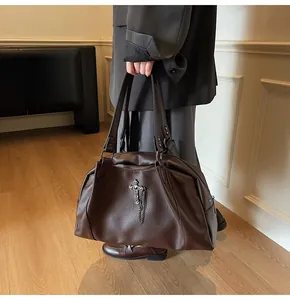 Close-up of large dark brown tote bag with cross chain and lychee grain texture