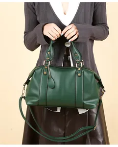 Detail view of dark green lychee grain leather boston bag with golden metal hardware and strap
