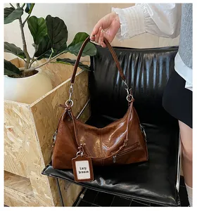 Detail of vintage brown oil wax leather shoulder bag with metallic zipper and knot decor