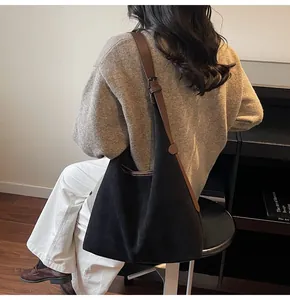 Detail of minimalist black suede hobo bag with adjustable brown leather shoulder strap