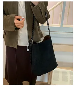 Detail einer schwarzen Wildleder-Eimertasche mit geflochtenem Riemen am Modell