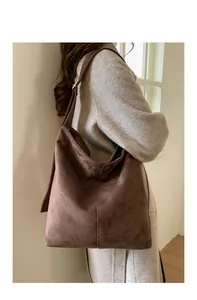 Close-up of retro brown suede tote bag with vertical stitching and gold buckle details