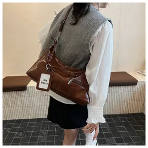 Close-up of brown polished leather crossbody bag with adjustable strap and metal zipper