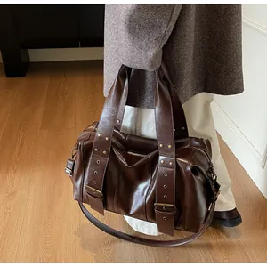 Detail view of large dark brown leather tote bag with wide strap and gold metal hardware