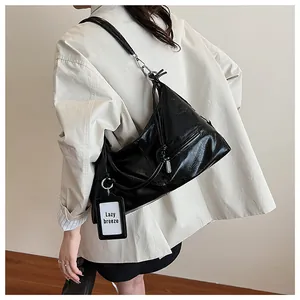 Detail of black glossy oiled leather hobo bag with silver zipper and adjustable strap
