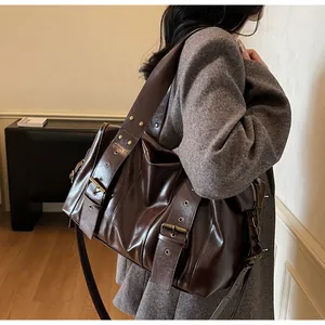 Detail of wide shoulder strap with bronze eyelets on a dark brown punk tote bag