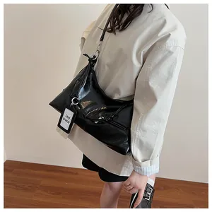 Detail of glossy black leather tote bag featuring silver ring hardware and knotted strap