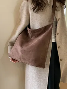 Minimalist chocolate brown suede tote bag styled with a beige coat in natural light