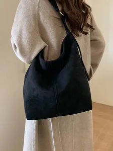 Minimalist black faux suede hobo tote bag with gold hardware shown on a model