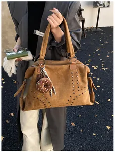 Détails du sac cabas en daim marron avec rivets en V et pendentif en peluche donut