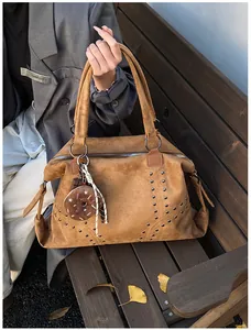Détail du cabas en daim marron avec rivets métalliques et charm beignet étoilé