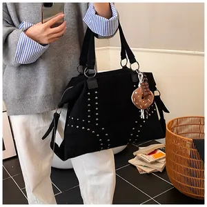 Détail du sac cabas en daim noir avec rivets argentés et pendentif chocolat ludique