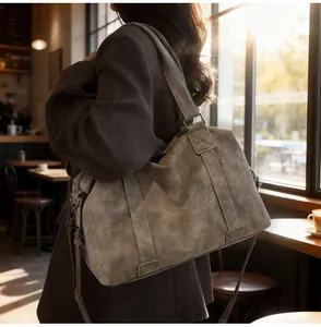 Large charcoal faux leather travel tote bag shown in a cozy cafe window setting