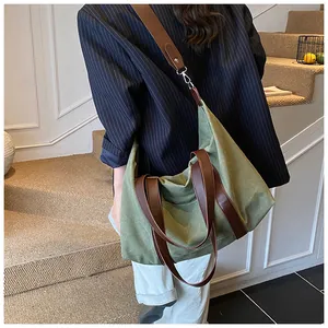 Detalle del bolso tote de lona verde oliva con asas de cuero marrón y correa ancha