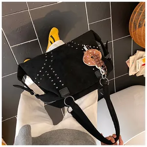 Gros plan sur un cabas en daim noir avec rivets argentés et charme donut
