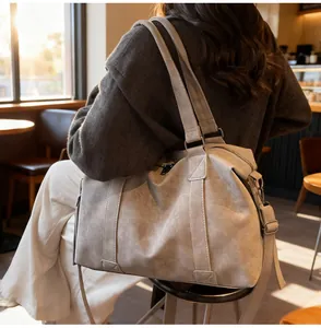 Detail of light grey large capacity tote bag with reinforced handles in a warm street setting
