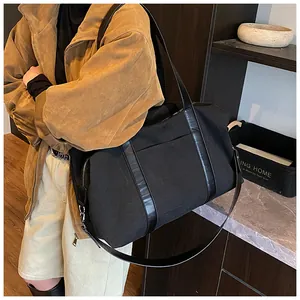 Detalle del bolso tote de lona negra con asas de cuero en estilo bandolera