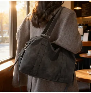 Detail of a large dark grey matte travel tote bag with reinforced straps in a cafe