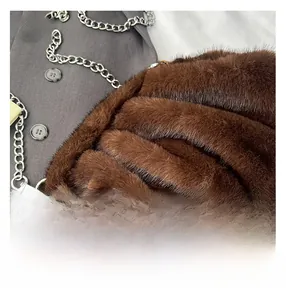 Macro detail of dark brown faux fur texture and silver chain strap on a plush cloud bag