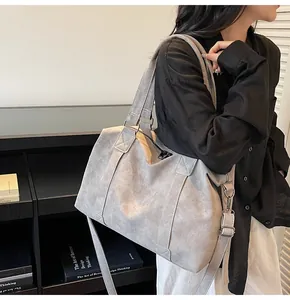 Detailed side view of large grey matte tote bag worn by a model in minimalist setting
