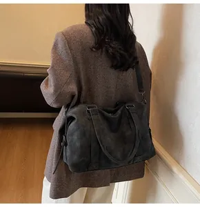 Detail view of large dark grey suede tote bag with adjustable shoulder strap and zippers