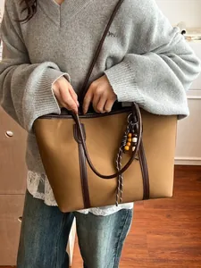 Brown contrast large tote bag with bead pendant charm shown in a casual commuter style