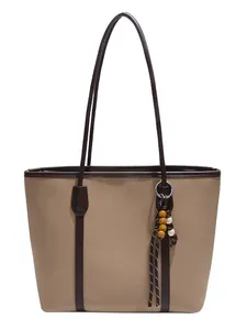 Large beige tote bag with dark brown trim and long straps, featuring a wooden bead charm