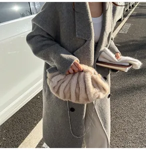 Detail of soft beige faux fur cloud bag with chic silver chain strap in sunlight