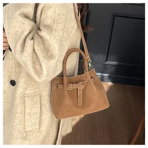 Vue détaillée d'un sac seau en cuir marron caramel avec surpiqûres blanches et boucle dorée