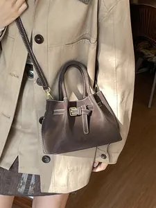 Retro dark brown leather bucket bag with white contrast stitching and belt buckle detail
