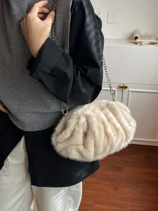 Chic cream white plush dumpling bag with silver chain strap shown in a cozy home setting