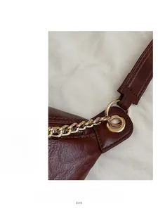 Detail of dark brown leather texture with golden chain hardware and smooth zipper closure