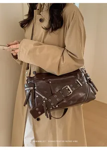Detail of dark brown oil wax leather shoulder bag with silver rivets and metal buckle strap
