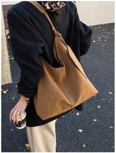 Brown frosted leather Hobo bag with white stitching detail shown in an outdoor street setting