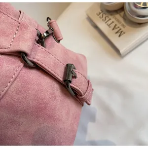 Detail of pink suede bag featuring premium gunmetal hardware and precise stitching