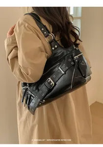 Detail of black punk shoulder bag with silver eyelets and zippers on a model back