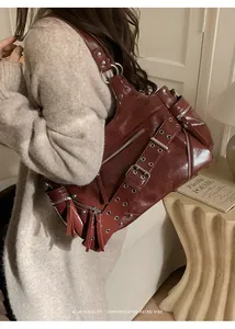 Detail of dark red oil wax leather shoulder bag with metallic studs and fringe tassels