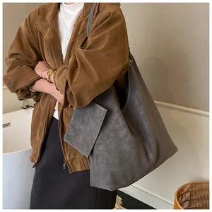 Detail of a large dark grey hobo tote bag and small square pouch in a soft suede-like finish