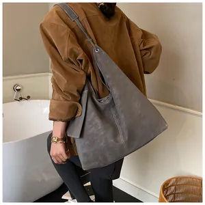 Deep grey suede shoulder bag shown on model highlighting its large size and soft texture