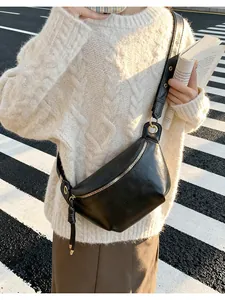 Detail view of the black crescent saddle bag with wide strap and gold zipper accents