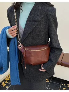 Close-up of retro brown leather crossbody bag with gold chain and refined texture